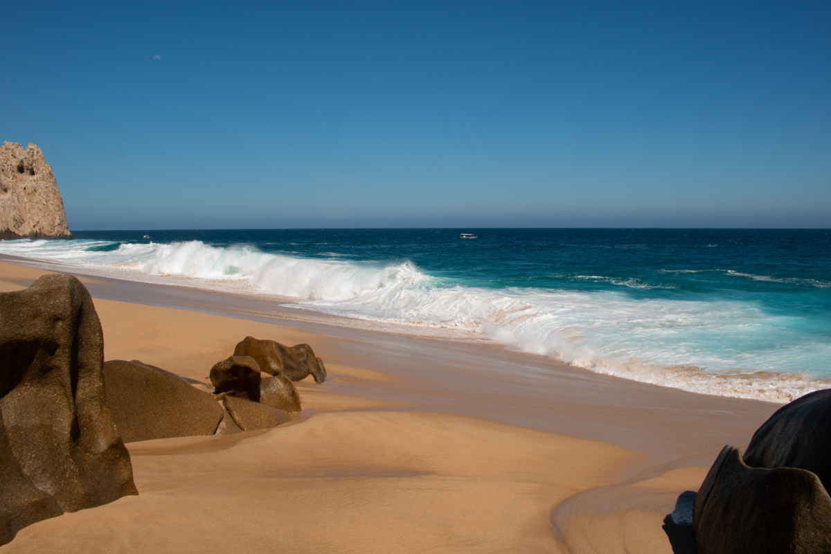 Beach view with sand, rocks, and ocean in Cabo San Lucas, Mexico