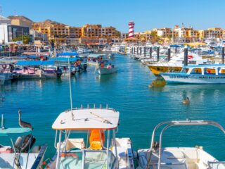 The colorful and busy cruise port with shops, cafes and boats in the marina along the Mexican Riviera at Cabo San Lucas, Mexico.