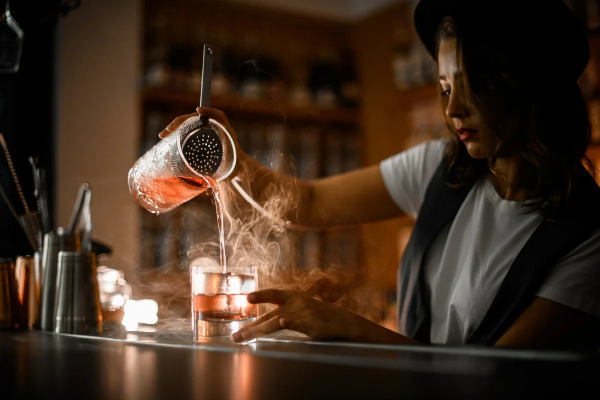 Woman in a speakeasy pouring a drink