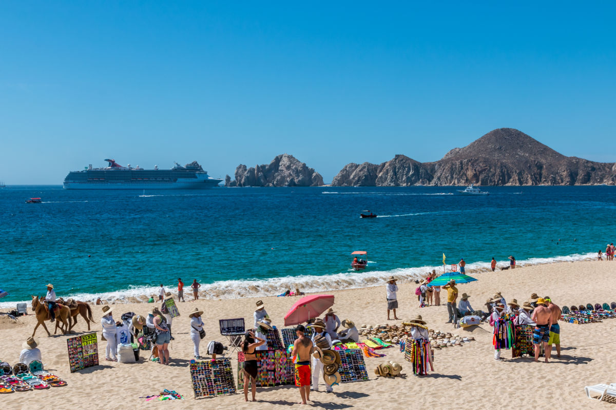 Cabo San Lucas, Mexico- Vendors sell there wares and services to tourists in front of a resort in Cabo San Lucas as a cruise ship enters the bay.