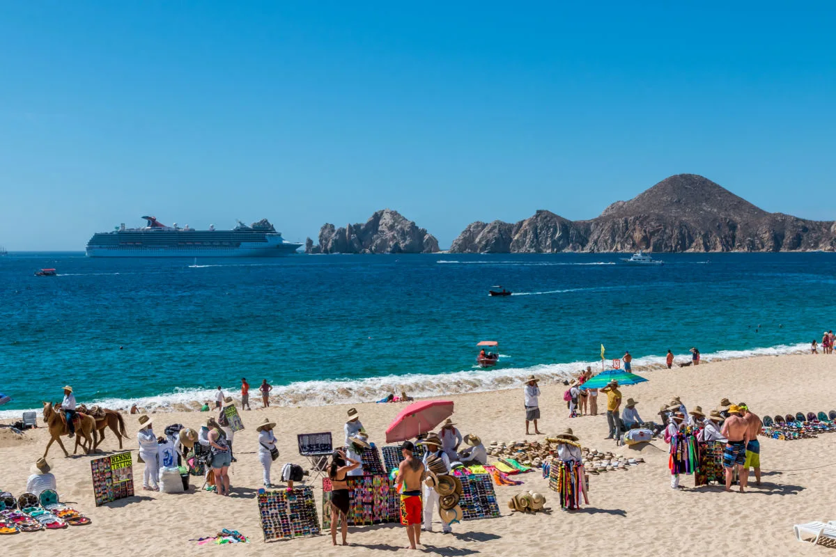 Cabo San Lucas, Mexico- Vendors sell there wares and services to tourists in front of a resort in Cabo San Lucas as a cruise ship enters the bay.