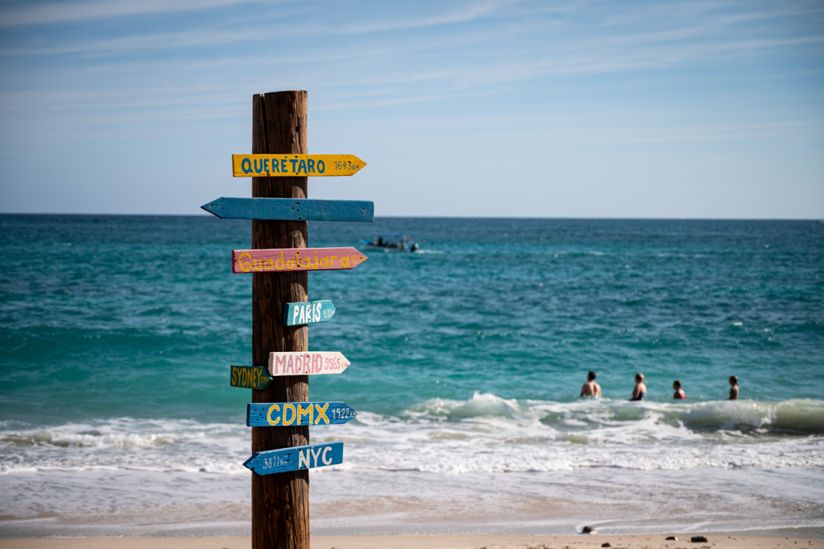 Sign at Cabo Pulmo in front of tourists in the ocean at the beach
