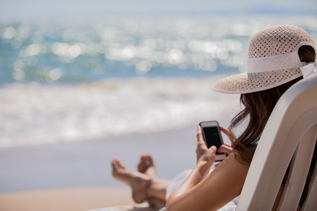 Woman on the beach on her phone using apps