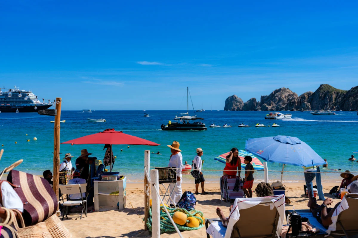 Entering Medano Beach via the Milky Beach Cabo sign entrance with the arch in the background