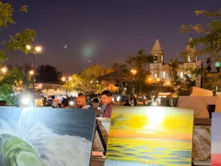 San Jose Del Cabo Art Walk at night with paintings in the foreground and church and moon in the background