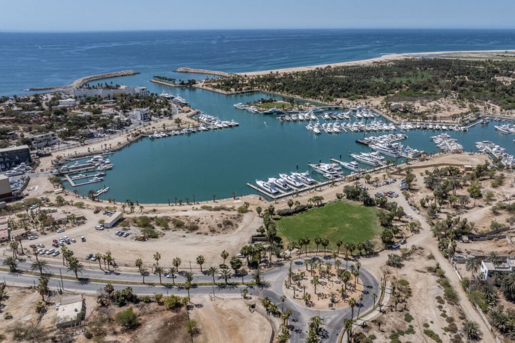 aerial landscape view of area around Marina at San José del Cabo (Puerto Los Cabos - Baja California Sur) with buildings, many boats and yachts moored at piers, as well as Pacific Ocean in background